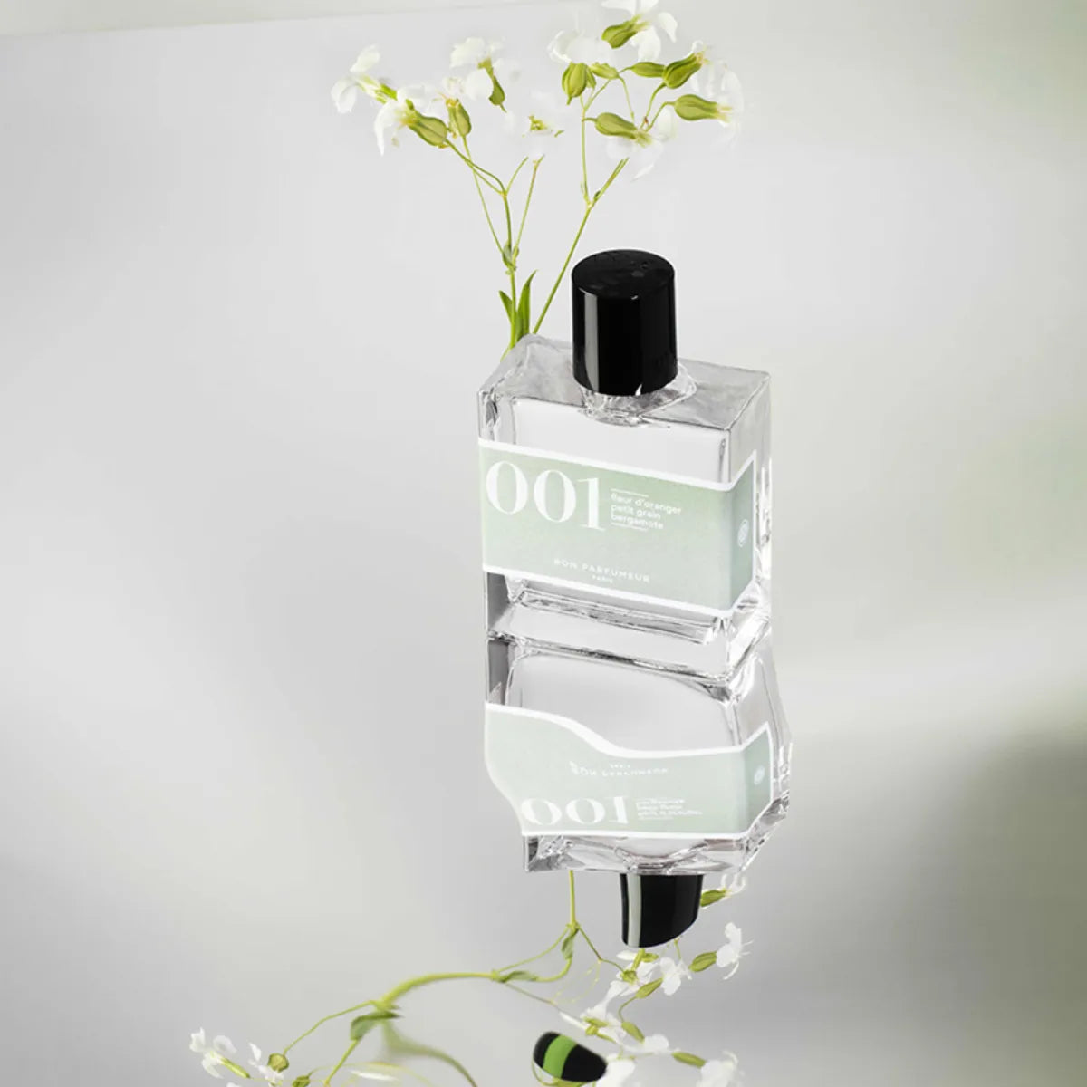 Bon Parfumeur - Les Classiques - 001 Parfümflakon mit hellem Etikett und schwarzem Verschluss auf reflektierender Oberfläche