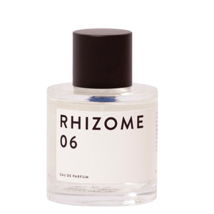 Rhizome - 06 zeigt klaren runden Flakon mit schlichtem weißen Etikett und dunklem Verschluss vor hellem Hintergrund