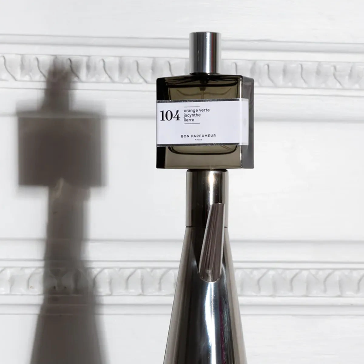 Bon Parfumeur - Les Privés - 104 Parfumflakon mit rauchigem Glas und weißem Etikett vor hell strukturiertem Hintergrund