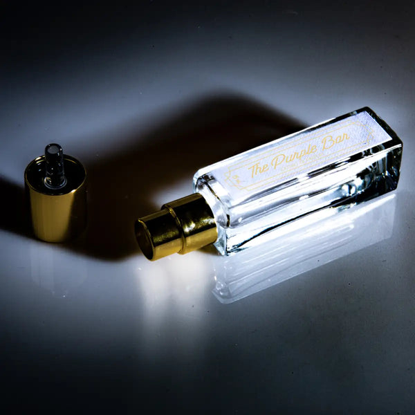 Cherigan - The Purple Bar klarer rechteckiger Parfumflakon mit goldenem Zerstäuber und abgenommenem Deckel auf dunklem Untergrund