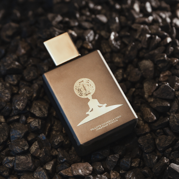 Spiritum - 33 - Cosmos Guide Parfumflakon in braun mit goldenem Verschluss auf dunklem, steinigem Untergrund