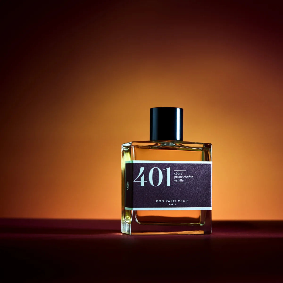 Bon Parfumeur - Les Classiques - 401 Parfümflakon mit dunkelrotem Etikett und schwarzem Verschluss vor warmem orangem Hintergrund