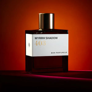 Bon Parfumeur - Les Extraits - 403 Myrrh Shadow Parfumflakon mit dunklem Glas und goldenem Verschluss vor tiefrotem Hintergrund