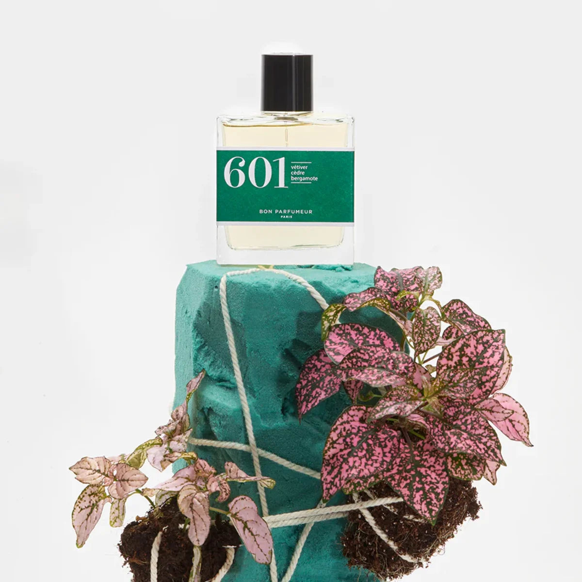 Bon Parfumeur - Les Classiques - 601 Parfumflakon mit grünem Etikett auf grünem Stein mit rosa Blättern vor weißem Hintergrund