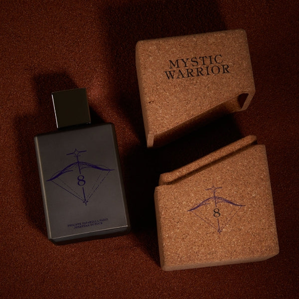 Spiritum - 8 - Mystic Warrior Parfumflakon mit dunklem Design neben Korkverpackung auf braunem Untergrund