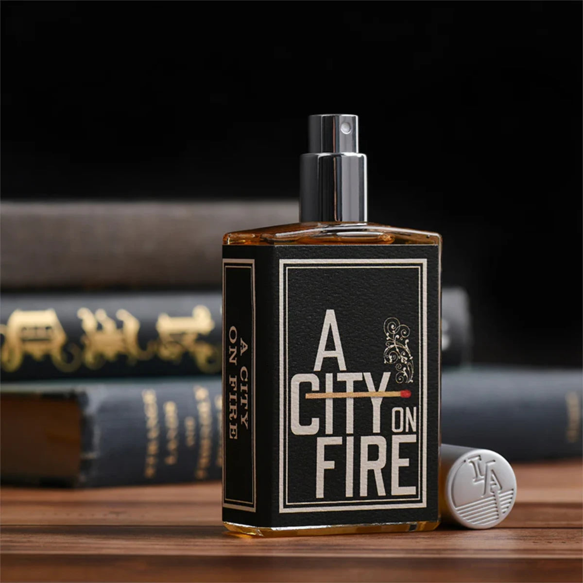 Imaginary Authors - A City on Fire Parfum im rechteckigen Flakon mit schwarzem Etikett und silbernem Zerstäuber auf Holztisch