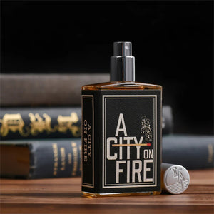 Imaginary Authors - A City on Fire Parfum im rechteckigen Flakon mit schwarzem Etikett und silbernem Zerstäuber auf Holztisch