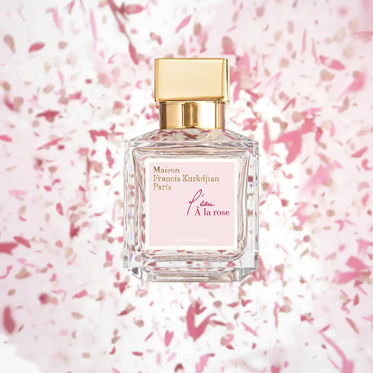Maison Francis Kurkdjian Paris - l'eau À la rose Parfumflakon mit goldfarbenem Deckel vor rosafarbenem Blütenhintergrund