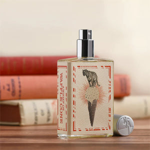Imaginary Authors - A Whiff of Wafflecone Parfumflakon mit Tigermotiv und silbernem Zerstäuber auf Holzfläche vor Büchern