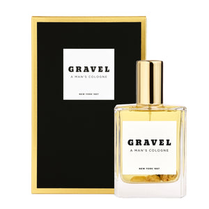 Gravel - A Man's Cologne Parfumflakon mit goldenem Deckel und rechteckiger Verpackung in Schwarz und Gold vor weißem Hintergrund