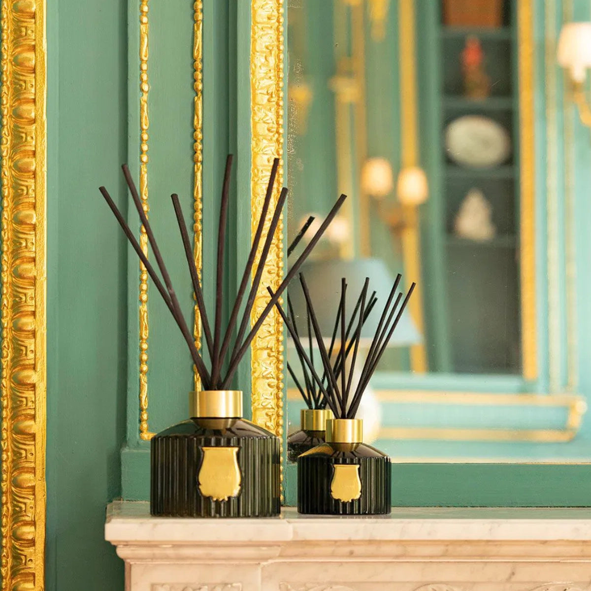 Trudon - Reed Diffusor - Abd el Kader mit dunkelgrünem Glas und goldfarbenem Verschluss vor opulentem Spiegelrahmen
