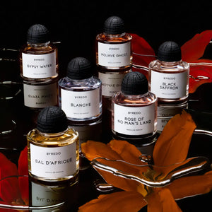 Byredo - Gypsy Water - Absolu de Parfum Flakon in dunklem Ambiente mit warmen Holzakzenten und roten Blättern