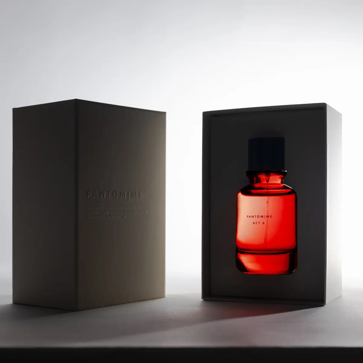 Pantomime - Act 6 Parfumflakon in rotem Glas mit schwarzem Verschluss in edler Geschenkbox vor hellem Hintergrund