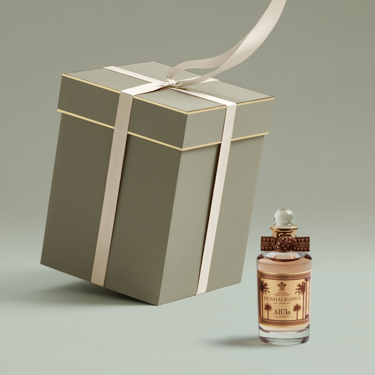 Penhaligon's - Trade Routes - AlUla Flakon mit dekorativem Verschluss neben elegant verpacktem Geschenk in gedeckten Farben