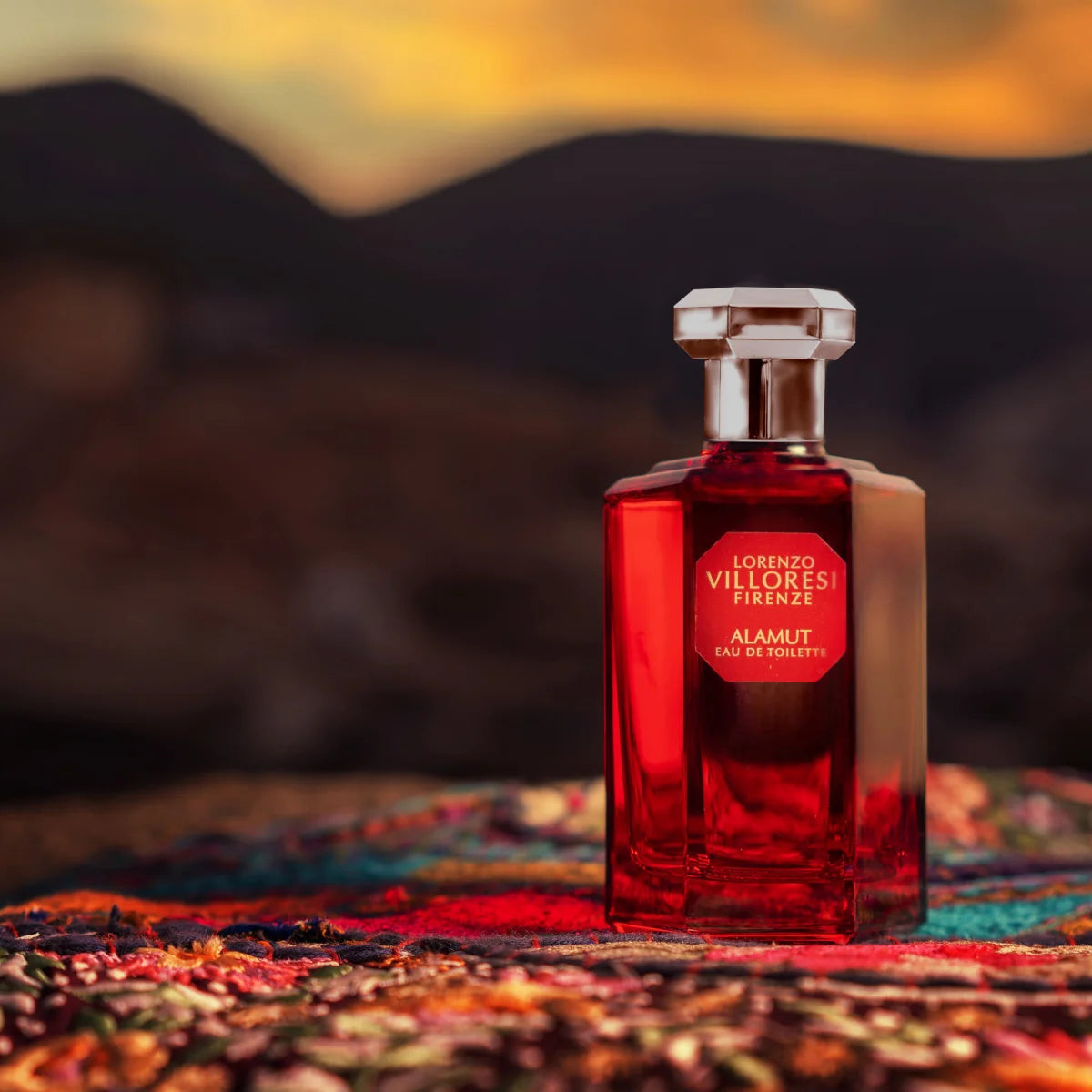 Lorenzo Villoresi - Alamut - EdT Parfumflakon in tiefrotem Glas mit facettiertem Verschluss vor abendlicher Naturkulisse