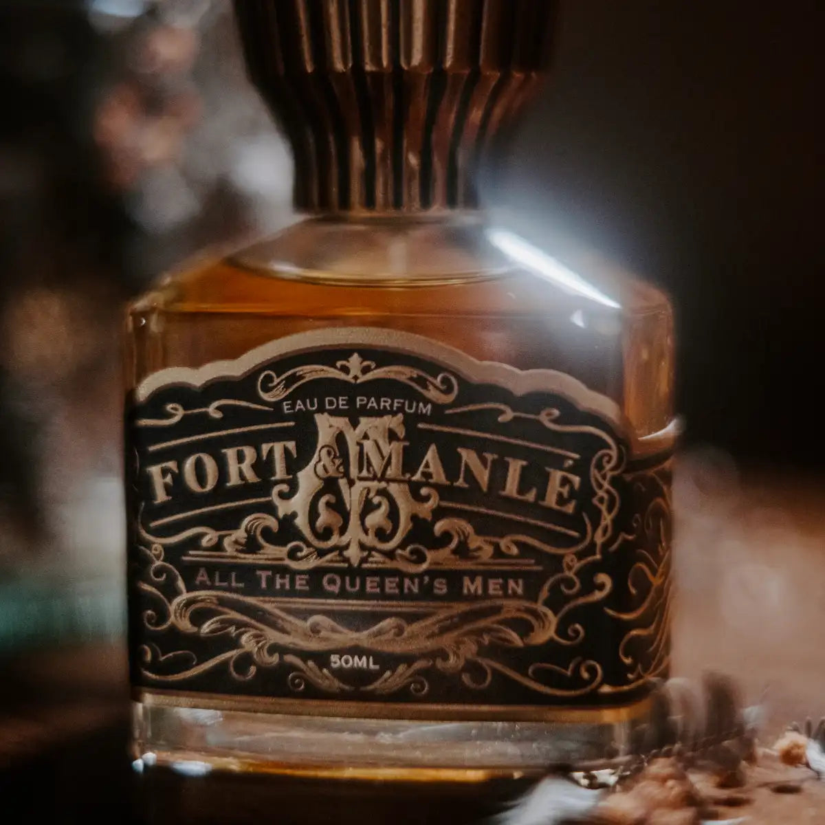 Fort & Manlé - All the Queen's Men Parfümflakon mit schwarzem, verziertem Etikett und warmem Lichtspiel