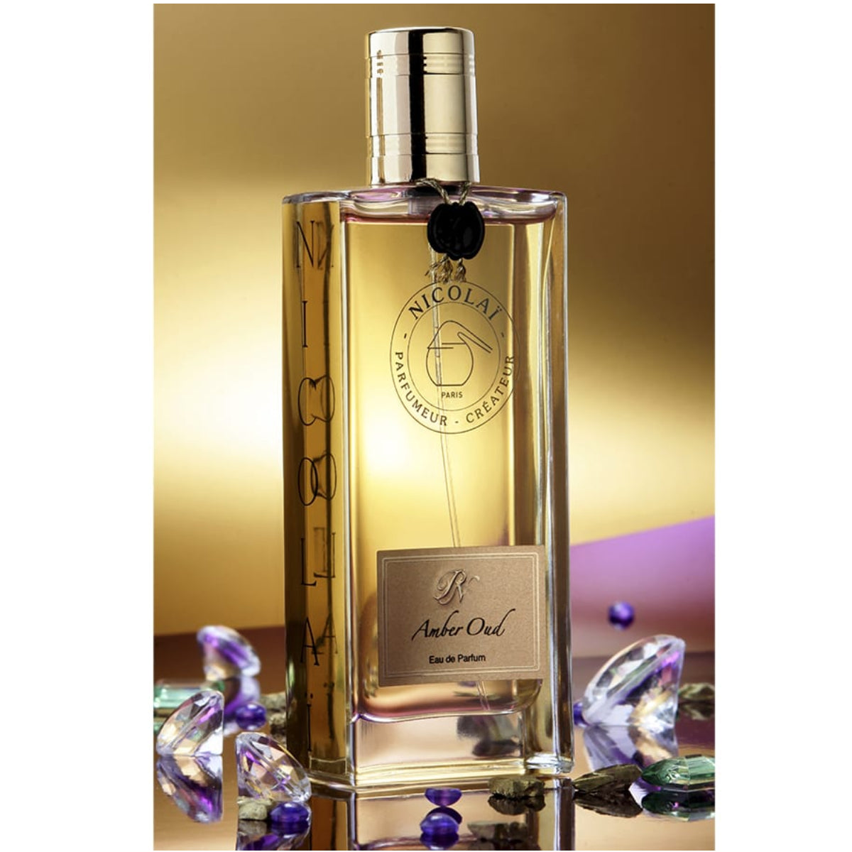 Nicolaï - Amber Oud Parfumflakon mit klarem Glas und goldfarbenem Verschluss, elegante Form mit edlem Label