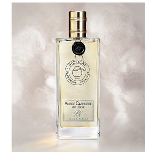 Nicolaï - Ambre Cashmere Intense Parfumflakon mit goldenem Verschluss vor cremigem, weich wirkendem Hintergrund