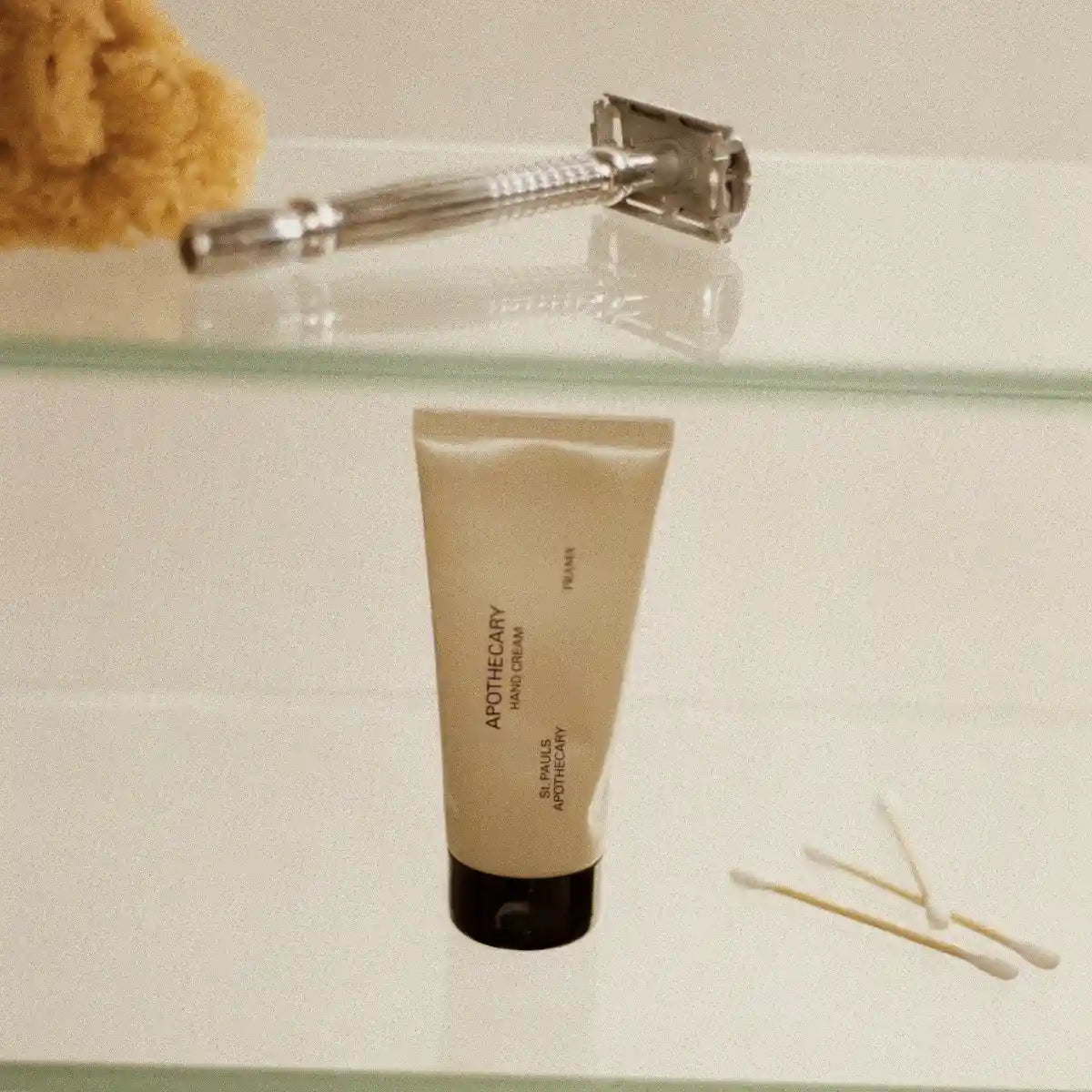 FRAMA - Apothecary - Hand Cream in einfacher Tube mit schwarzem Verschluss auf Glasregal mit Badeaccessoires