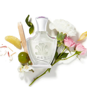 Creed - Acqua Fiorentina Parfumflakon mit klarer Glasflasche und zartem floralem Design, umgeben von frischen Blüten und Früchten