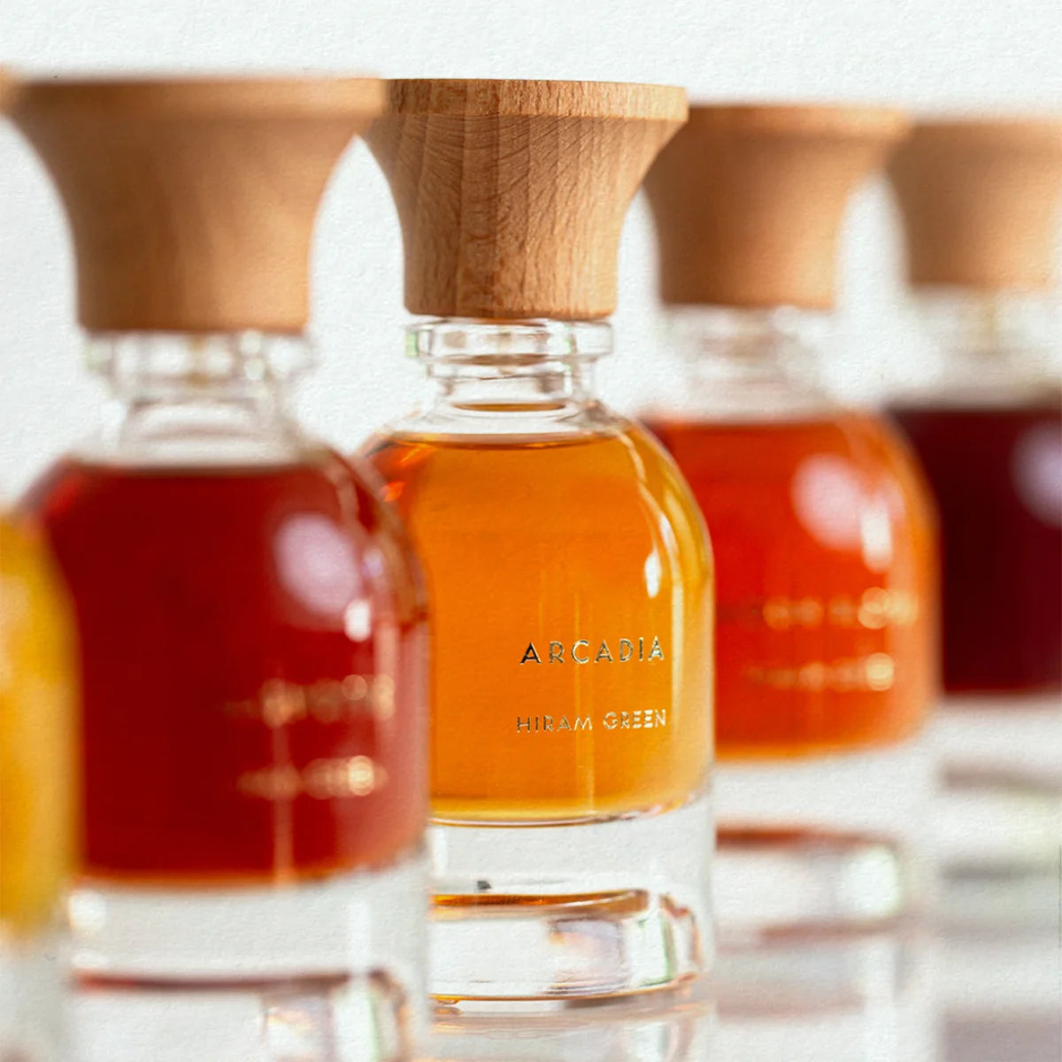 Hiram Green - Arcadia Parfumflakon mit goldgelber Flüssigkeit und markantem Holzverschluss vor hellem Hintergrund