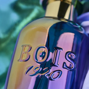 Bois 1920 - Trasparenti - Art1920 Flakon mit irisierendem Glas und goldfarbenem Verschluss in Nahaufnahme vor buntem Hintergrund
