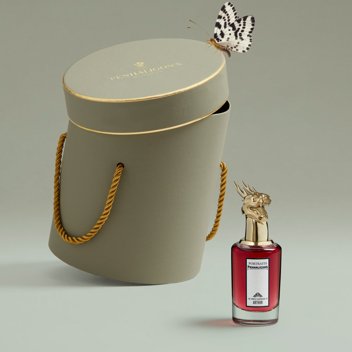Penhaligon's - Portraits - The World According to Arthur Parfumflakon mit rotem Glas und goldenem Hirschkopfverschluss neben edler Verpackung