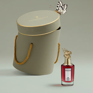 Penhaligon's - Portraits - The World According to Arthur Parfumflakon mit rotem Glas und goldenem Hirschkopfverschluss neben edler Verpackung