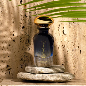 Widian - Sapphire Collection - Aswan Parfumflakon in dunkelblauem Glas mit goldenem Verschluss auf Natursteinen vor texturierter Wand