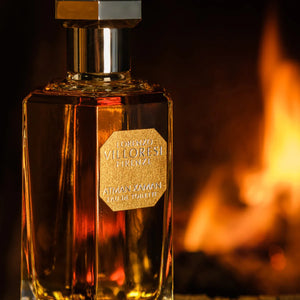 Lorenzo Villoresi - Atman Xaman - EDT Parfumflakon in bernsteinfarbenem Glas vor warmem Flammenhintergrund