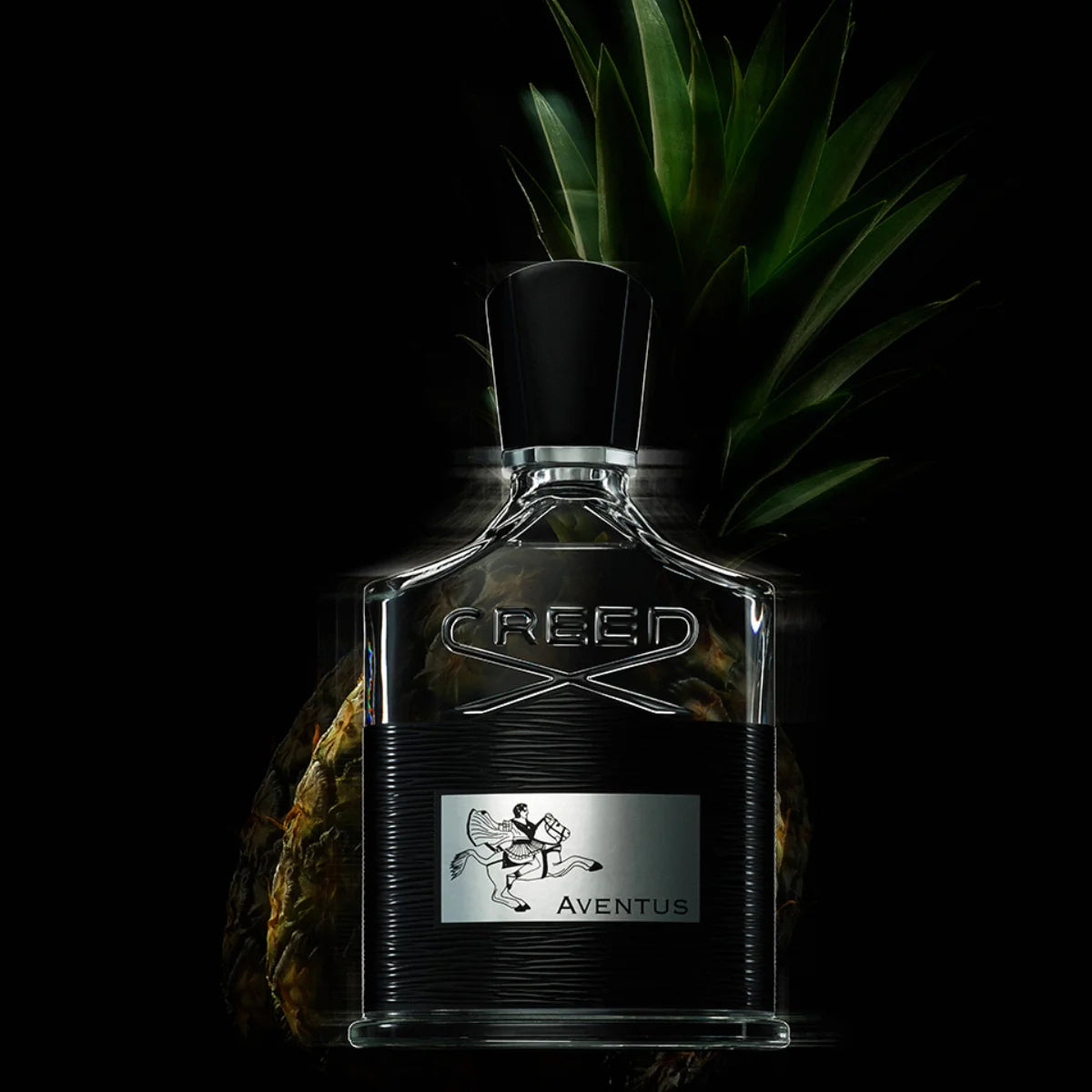 Creed - Aventus Parfumflakon mit markanter Gravur vor dunklem Hintergrund und frischer Ananas im Hintergrund