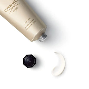 Creed - Aventus - Hand Cream goldfarbene Tube mit schwarzem Deckel und cremiger Textur auf weißem Hintergrund