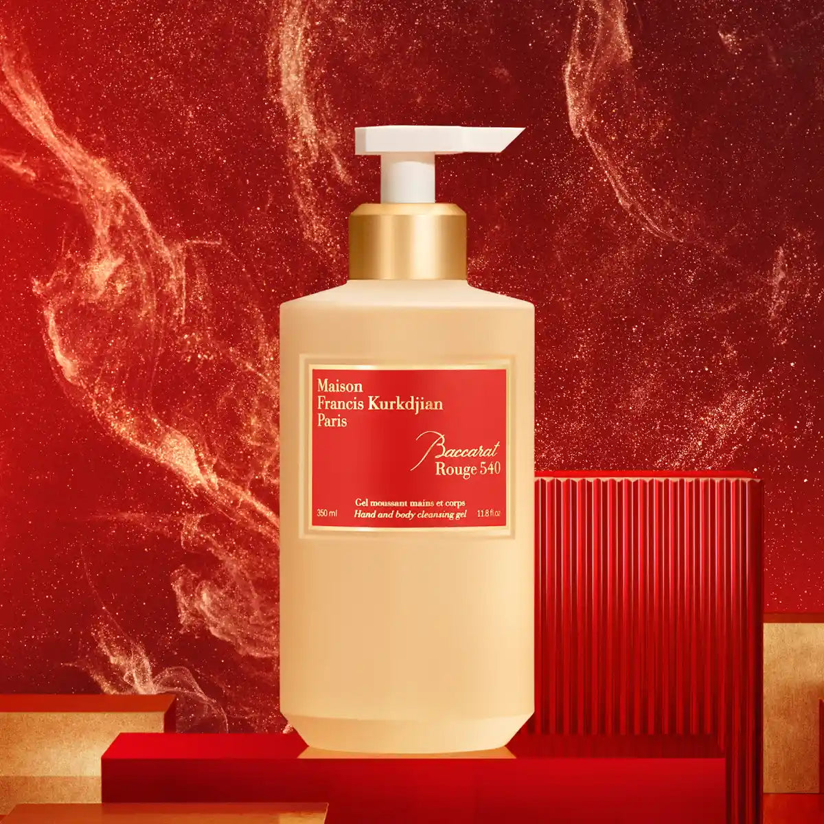 Maison Francis Kurkdjian Paris - Baccarat Rouge 540 - Hand & Body Cleansing Gel mit goldfarbenem Spender vor rotem Hintergrund