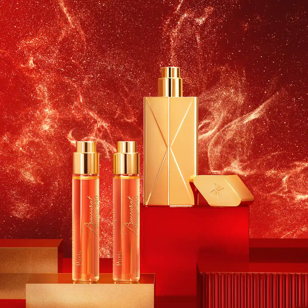 Maison Francis Kurkdjian Paris - Baccarat Rouge 540 - Travel Set mit elegantem goldenen Flakon und zwei Reisesprays vor rotem Hintergrund