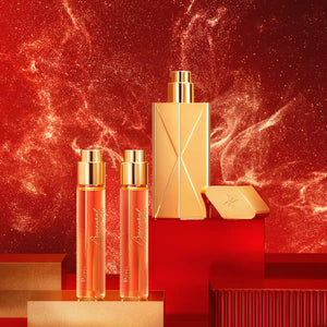 Maison Francis Kurkdjian Paris - Baccarat Rouge 540 - Travel Set mit elegantem goldenen Flakon und zwei Reisesprays vor rotem Hintergrund