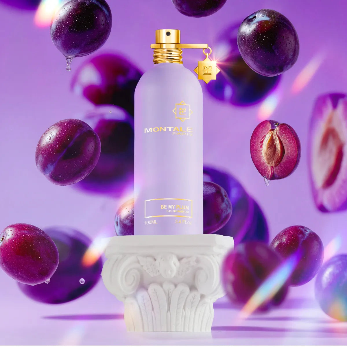 Montale - Be My Plum Parfumflakon in mattem Flieder mit goldenen Akzenten umgeben von frischen Pflaumen vor violettem Hintergrund