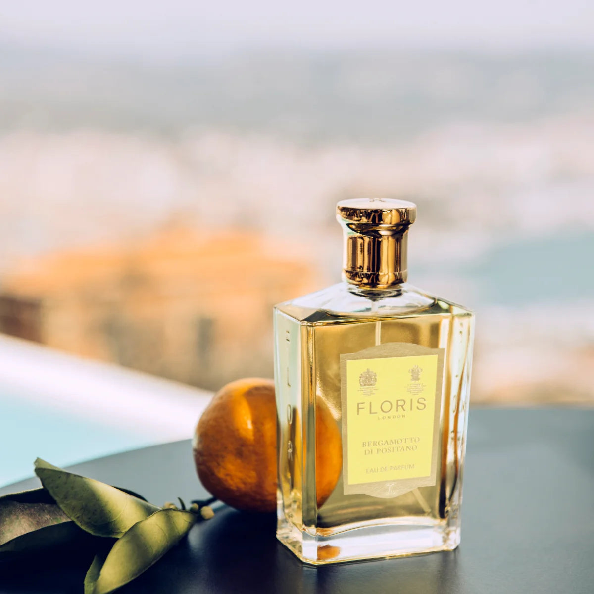 Floris - Bergamotto Di Positano Parfümflakon mit goldfarbenem Verschluss und sonnigem Hintergrund am Mittelmeerstrand