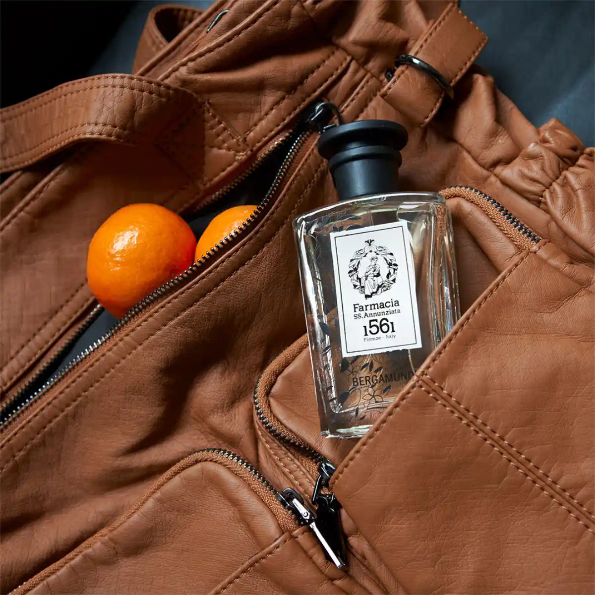 Farmacia SS. Annunziata - Bergamundi Parfumflakon mit schwarzem Deckel in brauner Tasche neben frischer Mandarine