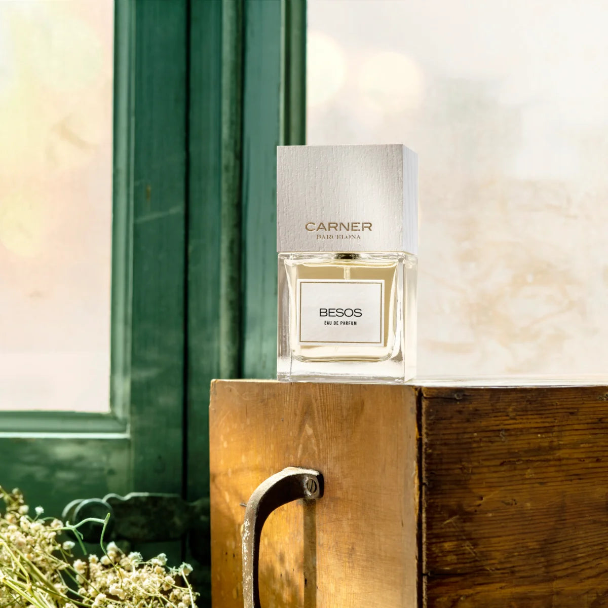 Carner Barcelona - Love Collection - BESOS Parfumflakon mit klarem Design und weißem Holzverschluss auf Holzuntergrund