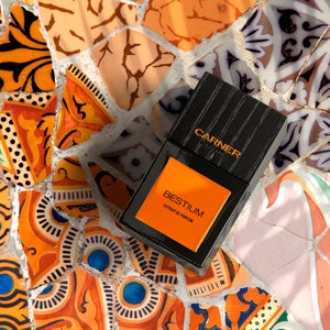 Carner Barcelona - Bestial Collection - Bestium Parfumflakon mit kräftigem Orange und schwarzem, strukturiertem Deckel auf buntem Mosaik