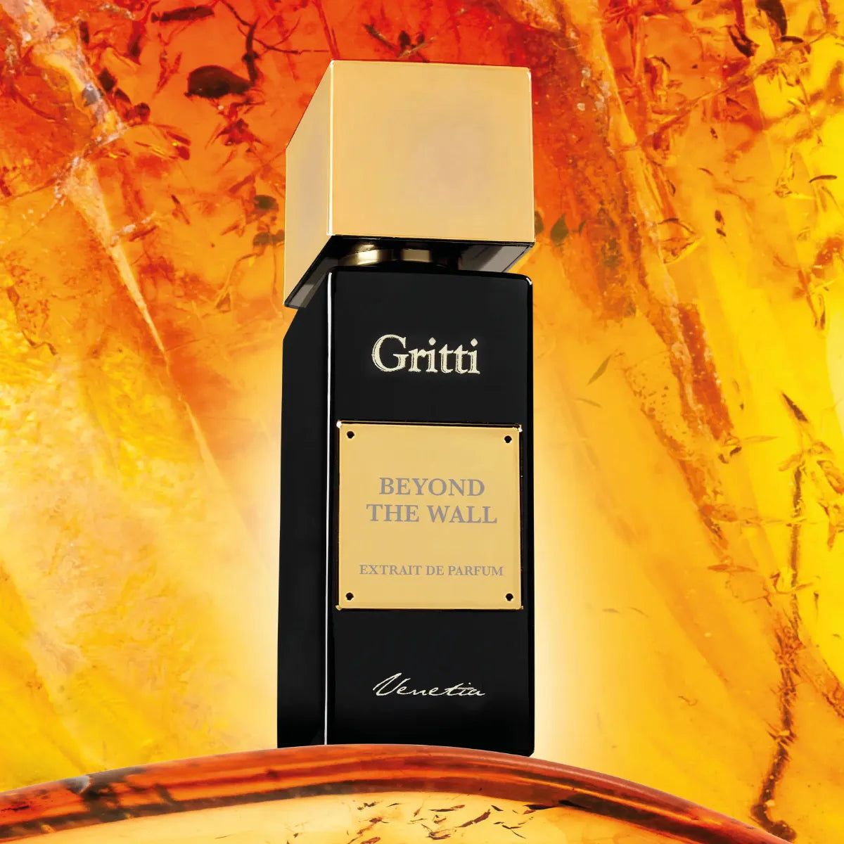 Gritti - Ivy Collection - Beyond the Wall Parfumflakon mit schwarzem Glas und goldenem Verschluss vor leuchtend orangefarbenem Hintergrund