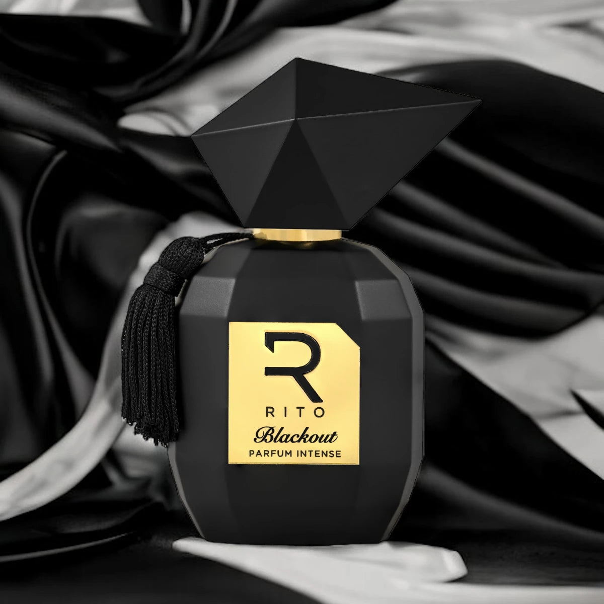 Rito - Blackout edle schwarze Flasche mit facettiertem Deckel und goldfarbenem Etikett vor Seidenstoff