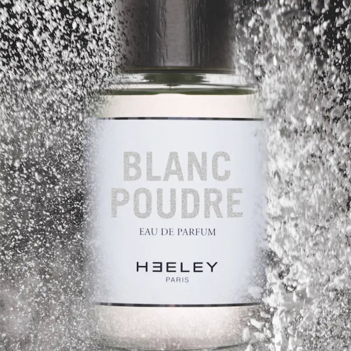 Heeley - Blanc Poudre Parfumflakon mit weißem Etikett und silbernem Deckel, umgeben von schimmerndem Pulvereffekt