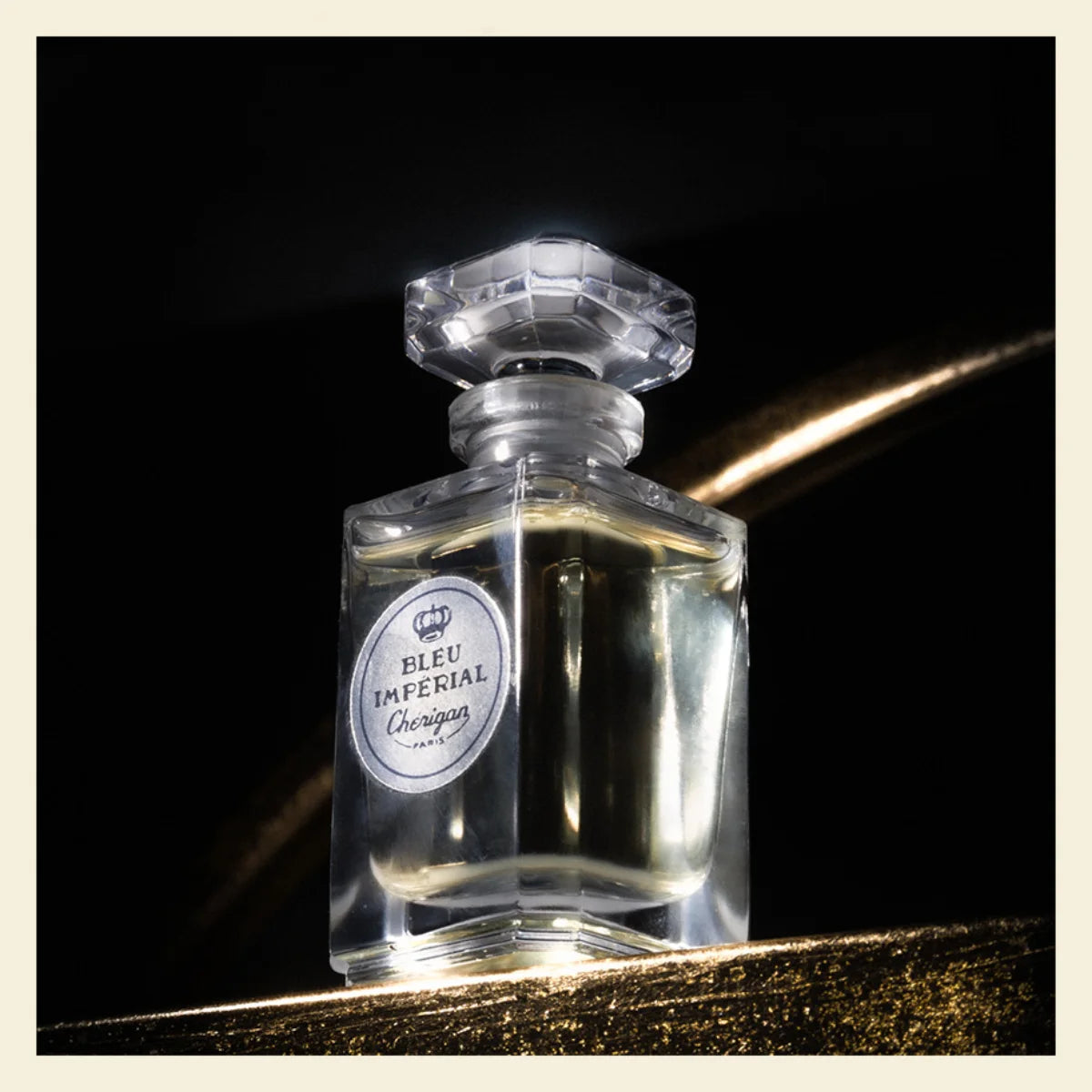 Cherigan - Bleu Imperial - Limited Edition klarer Flakon mit achteckigem Stopfen vor schwarzem Hintergrund und goldenem Lichtschimmer