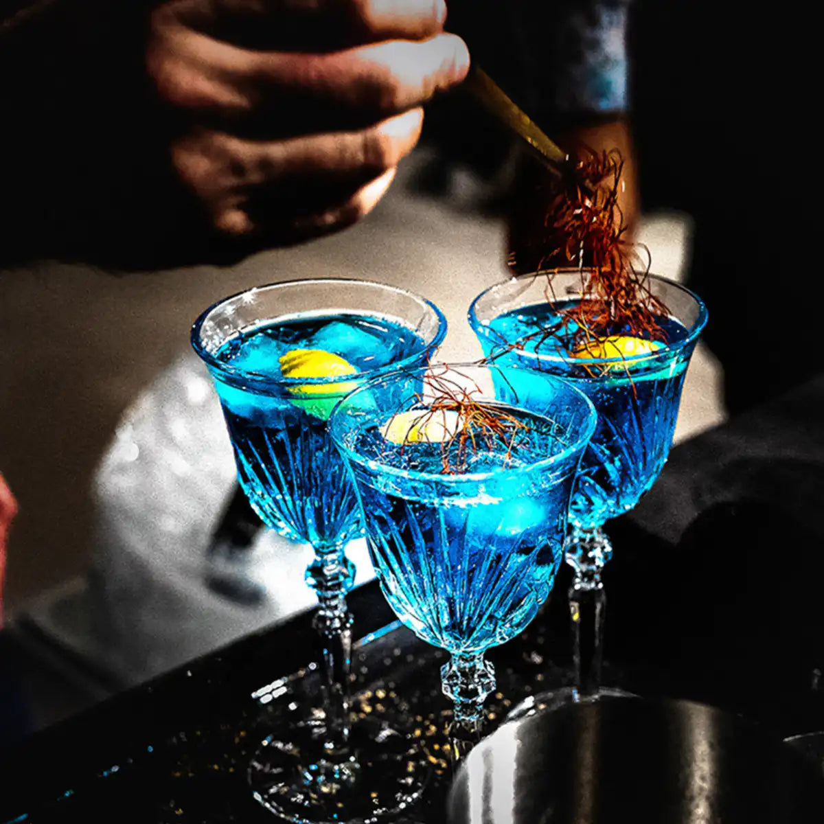 Cherigan - Bleu Imperial - Limited Edition zeigt drei elegante Gläser mit intensiv blauem Getränk und feiner Garnitur
