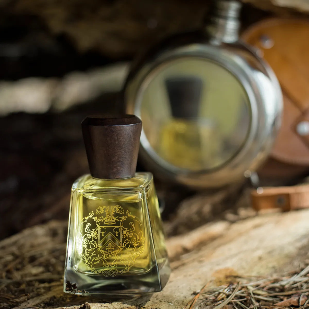 Frapin - Bonne Chauffe Flakon mit dunklem Holzverschluss vor rustikalem Hintergrund und Vintage-Accessoires im warmen Licht