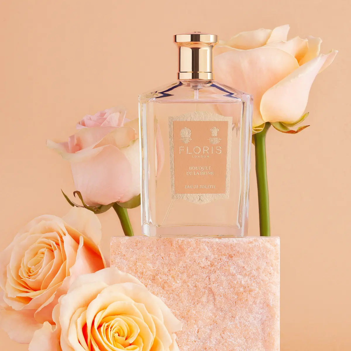 Floris - Bouquet de la Reine klarer Flakon mit goldenem Verschluss umgeben von zarten Pastellrosen auf beigem Hintergrund