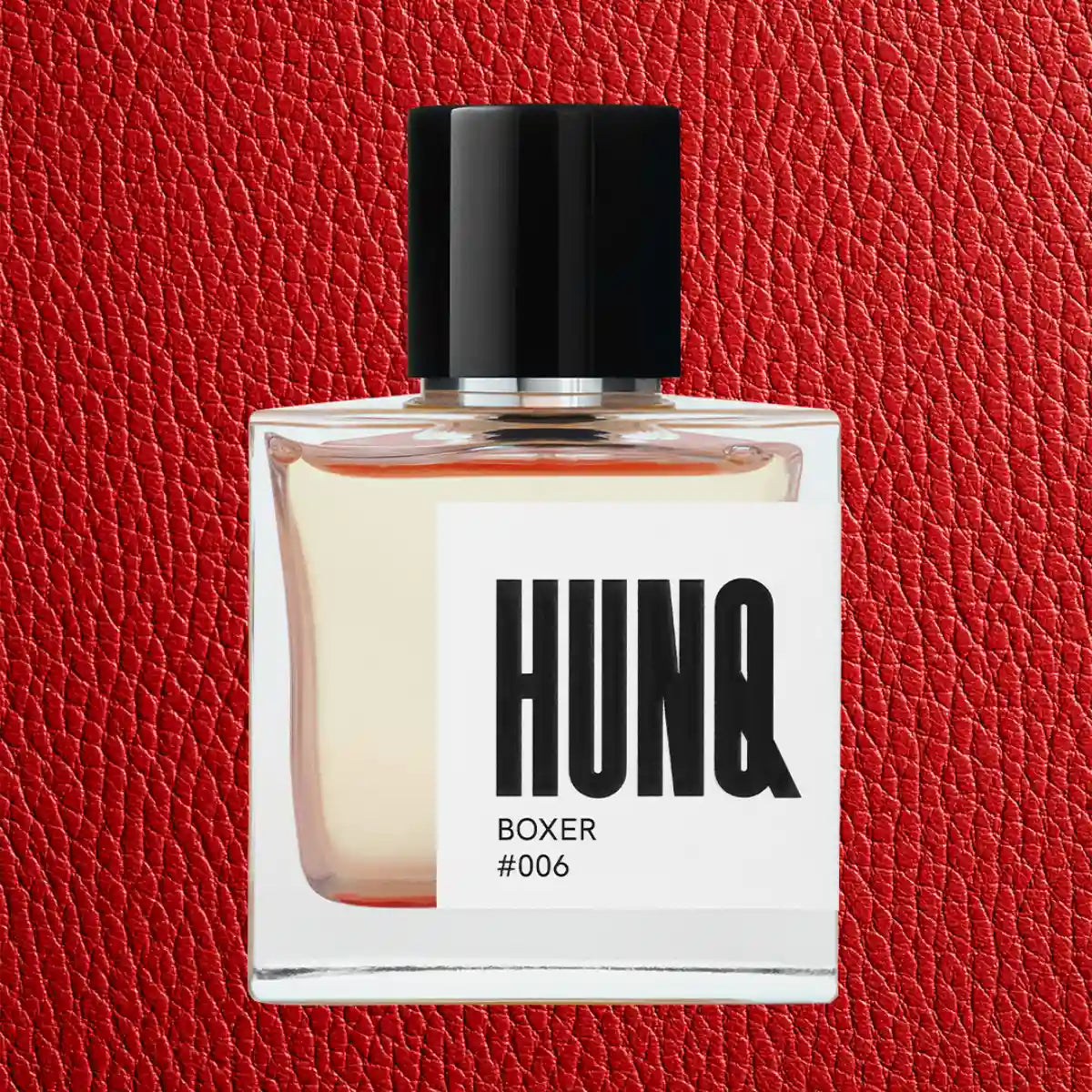 HUNQ - #006 Boxer klarer Flakon mit schwarzem Verschluss und markantem Etikett vor rotem Lederhintergrund