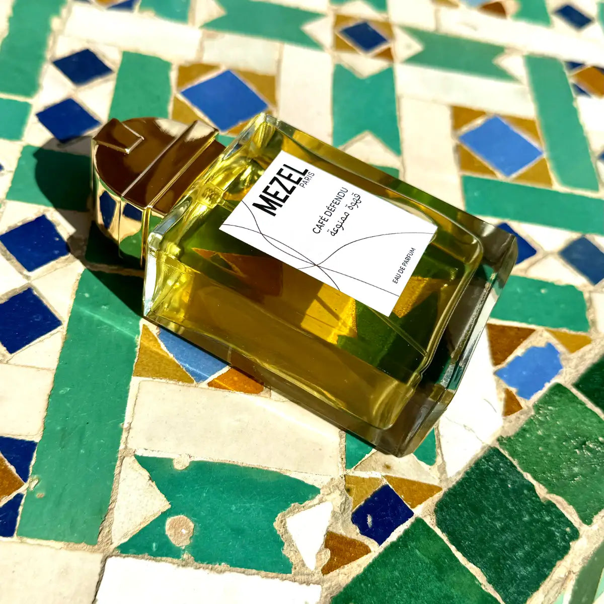 Mezel Paris - Café Défendu Parfumflakon mit goldenem Verschluss auf farbenfrohen marokkanischen Fliesen