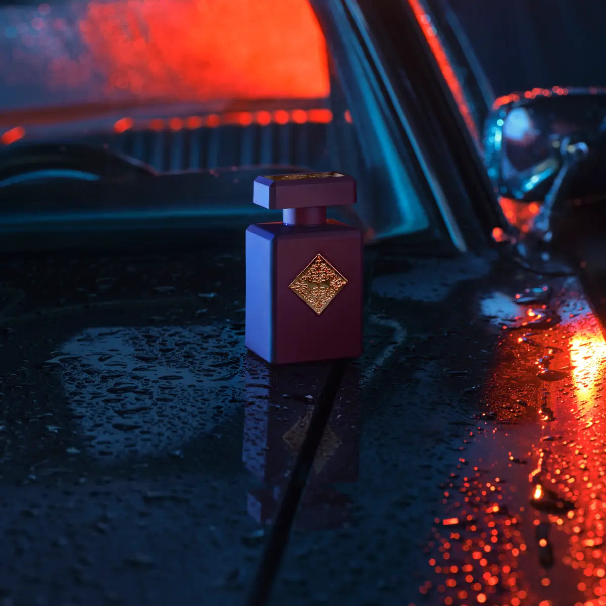 Initio - Carnal Blend - Can't get Enough Parfumflakon in tiefviolett mit goldenem Emblem auf regennassem Autodach bei Nachtlicht